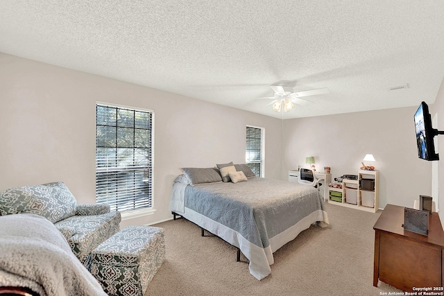 bedroom with a textured ceiling, light colored carpet, and ceiling fan