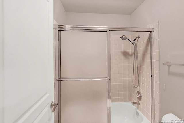 bathroom with bath / shower combo with glass door and toilet