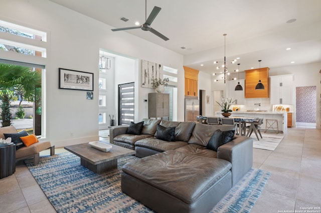 living area with recessed lighting, visible vents, a towering ceiling, light tile patterned flooring, and baseboards