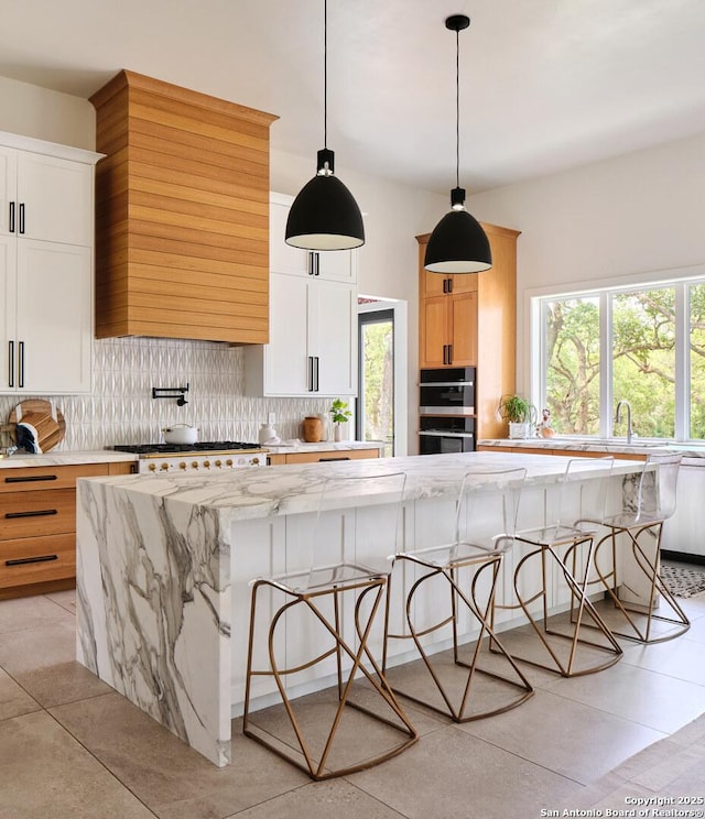 kitchen featuring a wealth of natural light, a large island, backsplash, and a kitchen breakfast bar