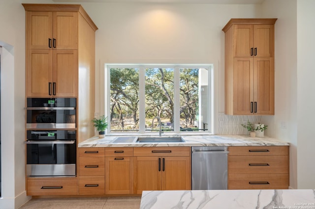 kitchen featuring stainless steel appliances, a sink, decorative backsplash, and light stone countertops