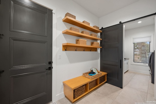 mudroom featuring light tile patterned floors, a barn door, and baseboards