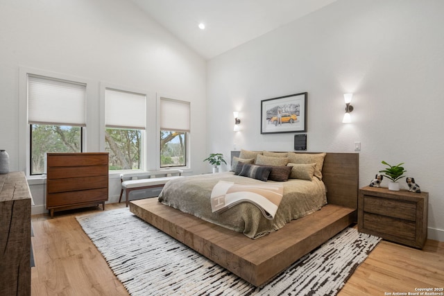 bedroom with light wood-style floors, recessed lighting, high vaulted ceiling, and baseboards