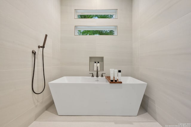 bathroom featuring tile walls and a freestanding bath