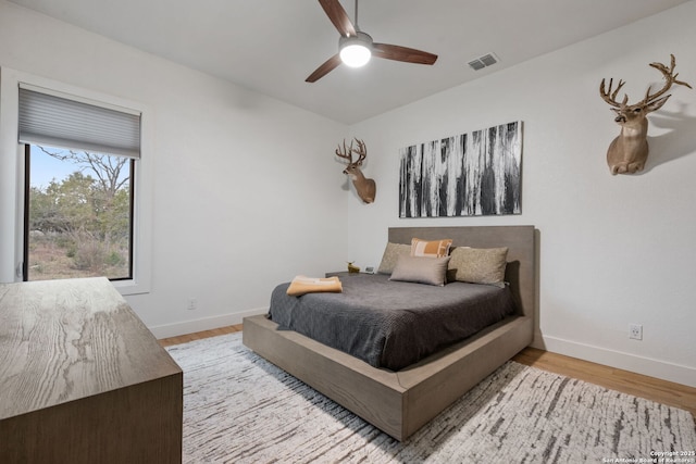 bedroom featuring visible vents, ceiling fan, baseboards, and wood finished floors