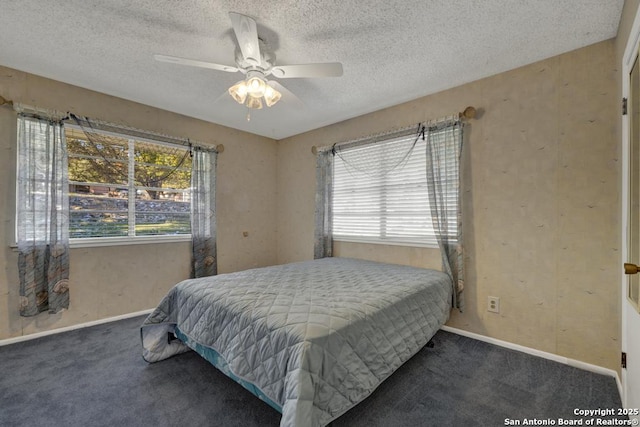 bedroom featuring dark colored carpet, a textured ceiling, and ceiling fan