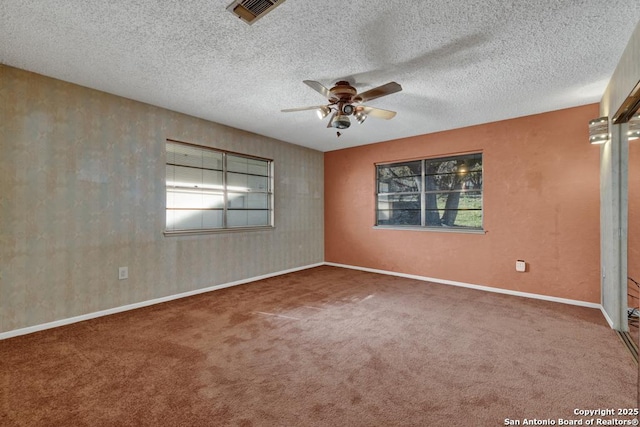 carpeted empty room with ceiling fan, a healthy amount of sunlight, and a textured ceiling