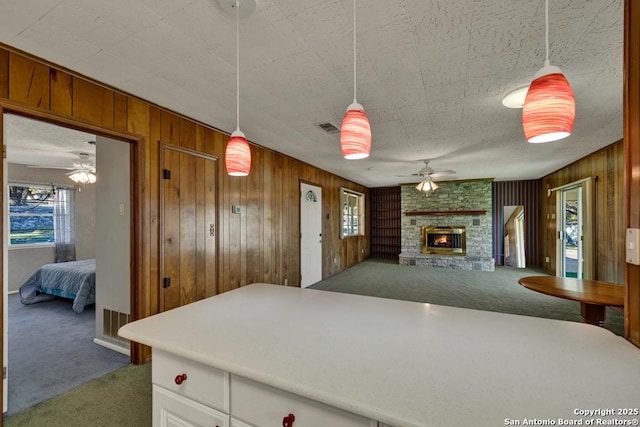 kitchen featuring ceiling fan, a fireplace, dark carpet, and hanging light fixtures