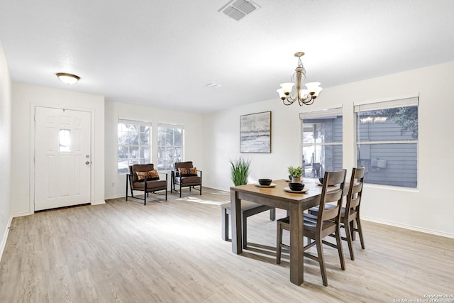 dining space featuring a chandelier, light hardwood / wood-style flooring, and a textured ceiling