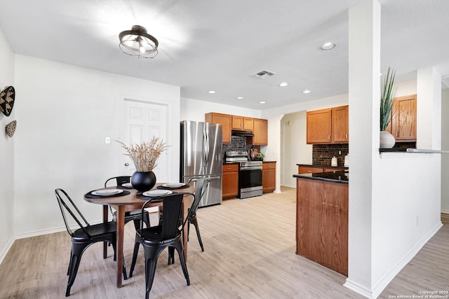 kitchen with stainless steel appliances, light wood-type flooring, and decorative backsplash