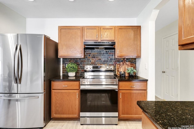 kitchen featuring appliances with stainless steel finishes, dark stone countertops, and decorative backsplash