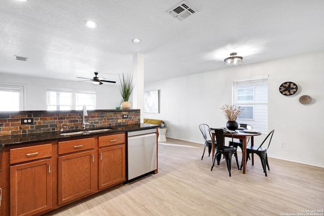 kitchen featuring sink, tasteful backsplash, a textured ceiling, stainless steel dishwasher, and light hardwood / wood-style floors