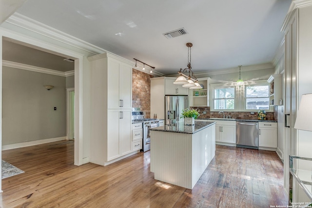 kitchen featuring tasteful backsplash, white cabinetry, a center island, dark stone counters, and stainless steel appliances