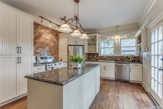 kitchen featuring sink, appliances with stainless steel finishes, white cabinets, a kitchen island, and decorative light fixtures