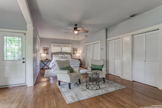 bedroom with multiple closets, ceiling fan, and wood-type flooring