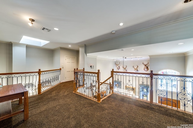 hallway with ornamental molding, carpet flooring, and a skylight