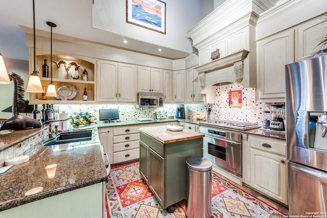 kitchen featuring sink, wooden counters, stainless steel appliances, a kitchen island, and decorative light fixtures