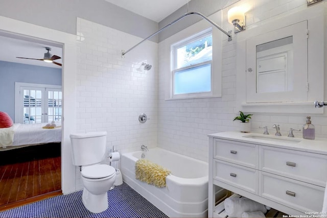 full bathroom with toilet, tiled shower / bath, vanity, ceiling fan, and decorative backsplash