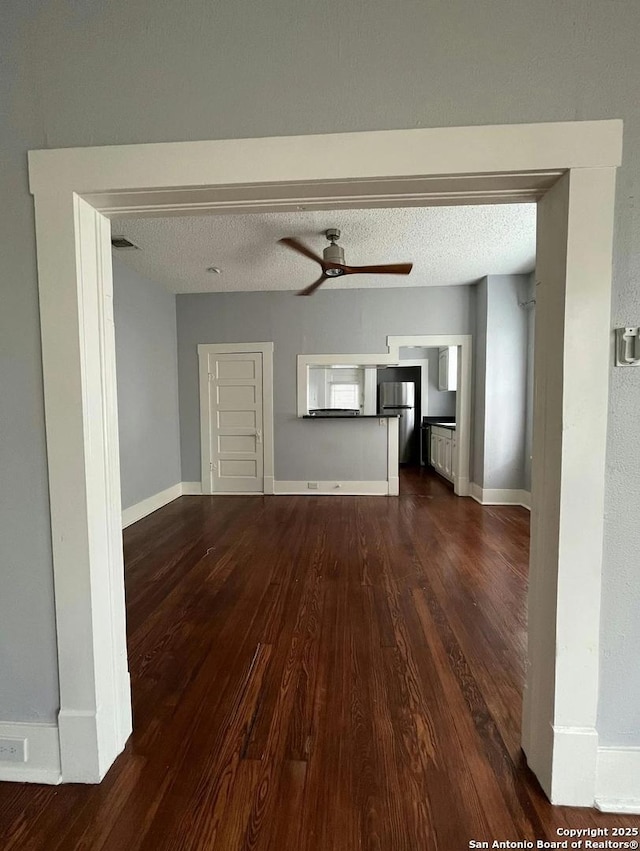 unfurnished living room with ceiling fan, dark hardwood / wood-style flooring, and a textured ceiling