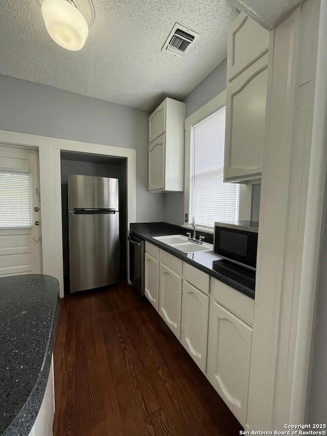 kitchen with dark hardwood / wood-style floors, a wealth of natural light, white cabinetry, sink, and stainless steel appliances