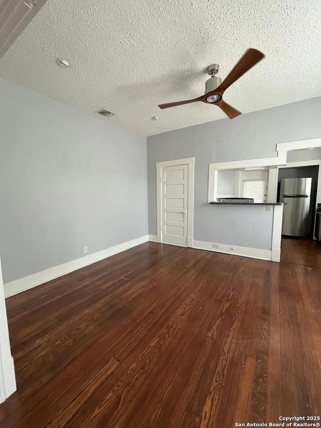 unfurnished living room with dark wood-type flooring, a textured ceiling, and ceiling fan