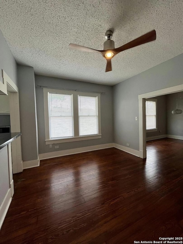 unfurnished living room featuring dark hardwood / wood-style floors, a textured ceiling, and ceiling fan