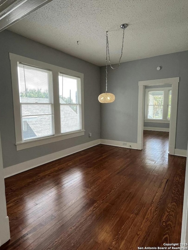 unfurnished dining area with dark hardwood / wood-style flooring and a textured ceiling