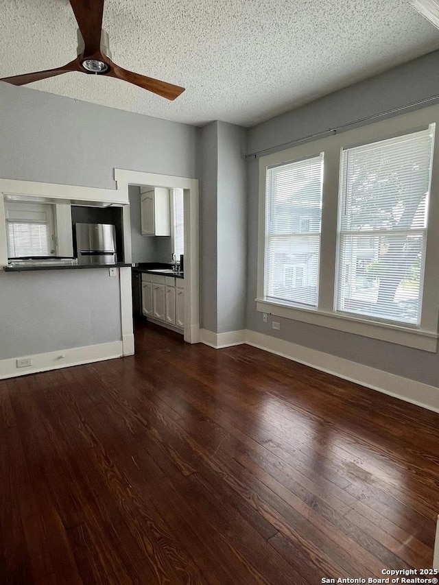 unfurnished living room with dark hardwood / wood-style floors, sink, a textured ceiling, and ceiling fan