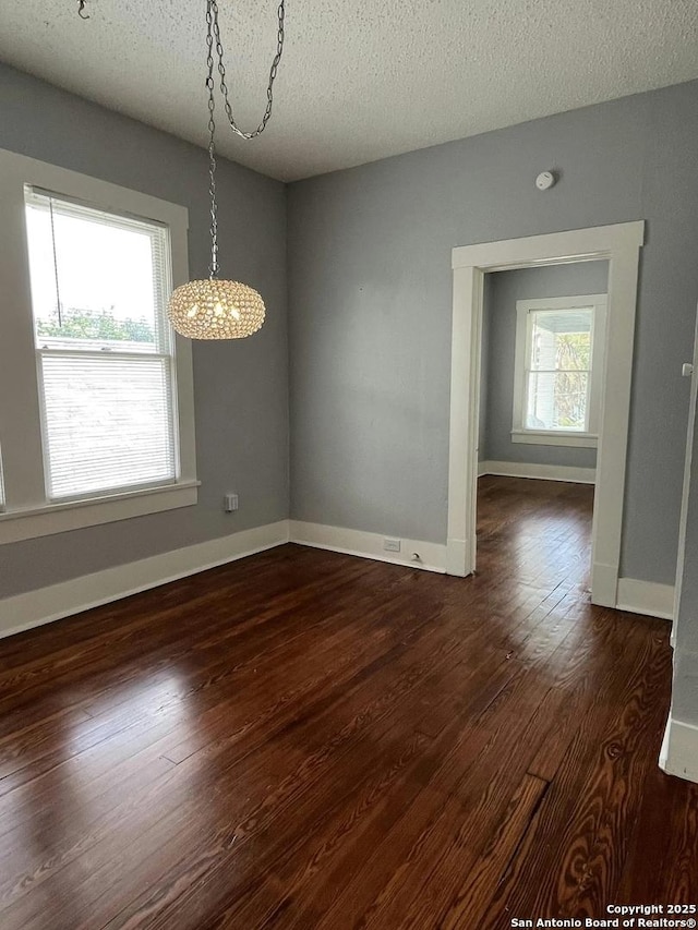 unfurnished dining area featuring dark wood-type flooring and a textured ceiling