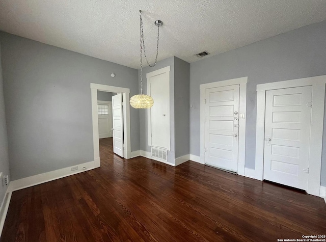 unfurnished dining area featuring dark hardwood / wood-style flooring and a textured ceiling