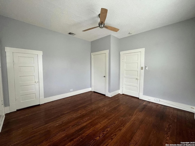 unfurnished bedroom with dark wood-type flooring, ceiling fan, and a textured ceiling