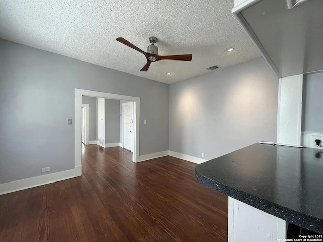 unfurnished living room featuring ceiling fan, dark wood-type flooring, and a textured ceiling