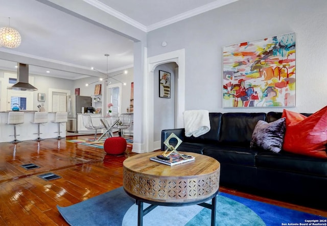 living room featuring wood-type flooring, ornamental molding, and an inviting chandelier