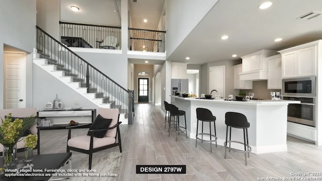 kitchen featuring a breakfast bar, tasteful backsplash, appliances with stainless steel finishes, an island with sink, and white cabinets