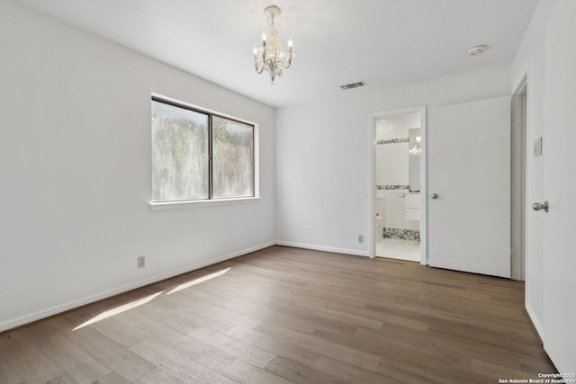 12519 Elm Manor St, San Antonio, TX 78230 - unfurnished bedroom with a chandelier, wood finished floors, baseboards, and connected bathroom