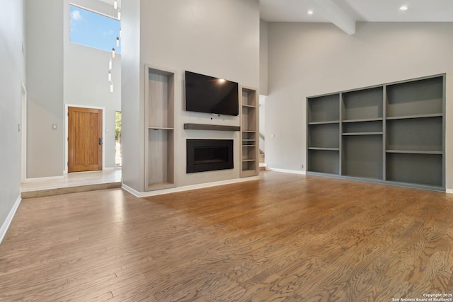 12519 Elm Manor St, San Antonio, TX 78230 - unfurnished living room with a high ceiling, wood finished floors, baseboards, plenty of natural light, and a fireplace