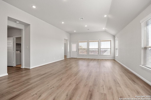 unfurnished living room featuring lofted ceiling, washer / dryer, and light hardwood / wood-style floors