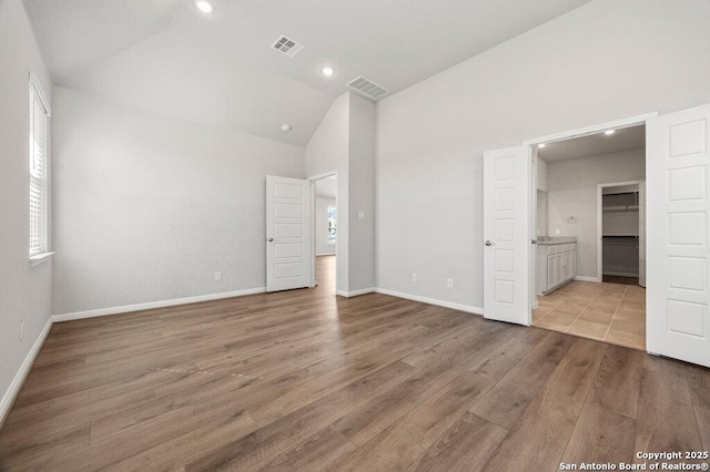 unfurnished bedroom with lofted ceiling, a spacious closet, and light wood-type flooring