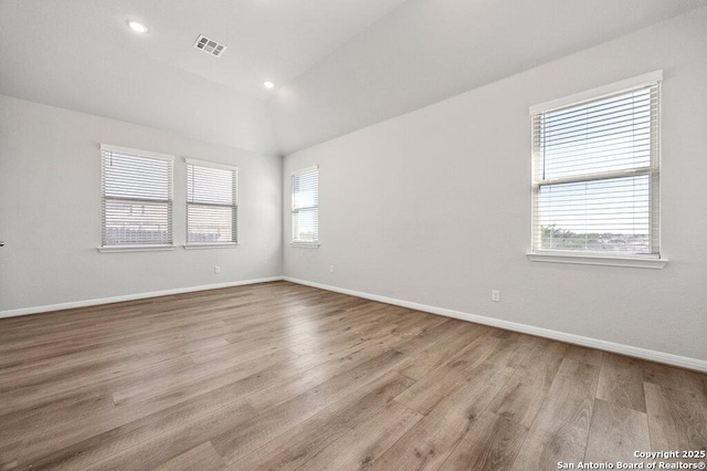 empty room with lofted ceiling and light hardwood / wood-style flooring