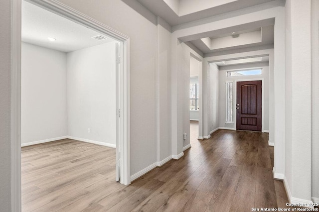 entryway with a tray ceiling and light wood-type flooring