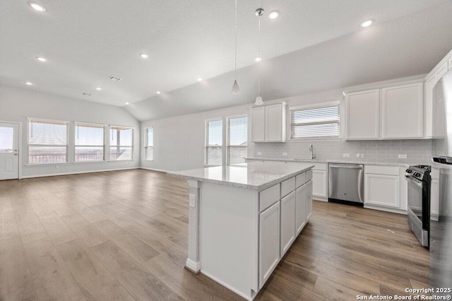 kitchen with lofted ceiling, light stone counters, white cabinetry, and stainless steel appliances