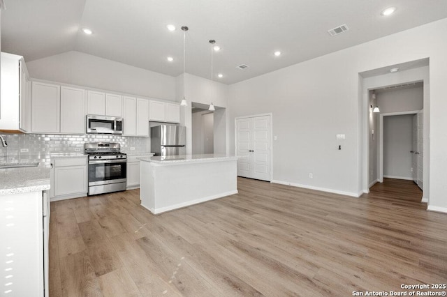 kitchen featuring sink, appliances with stainless steel finishes, white cabinetry, hanging light fixtures, and a center island