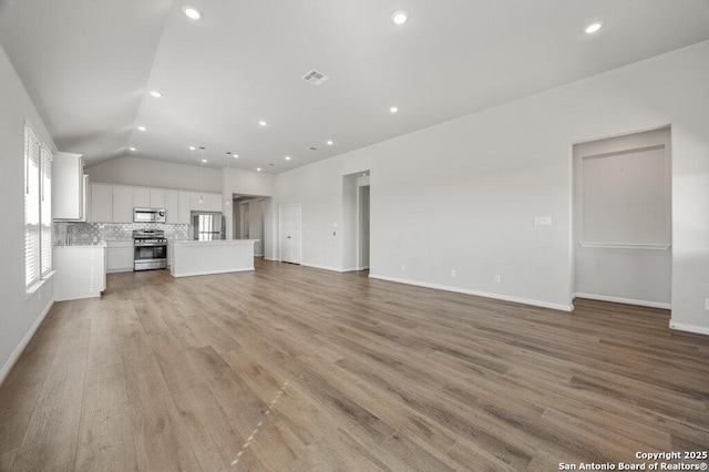 unfurnished living room featuring vaulted ceiling and light hardwood / wood-style floors