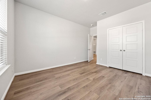 unfurnished bedroom featuring light hardwood / wood-style flooring and a closet