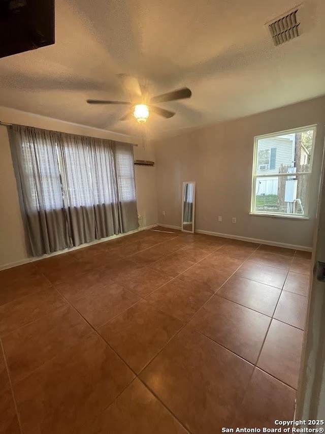 tiled spare room featuring ceiling fan