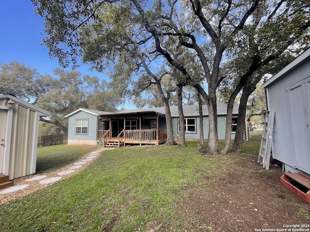 back of house with a yard, a deck, and a storage unit