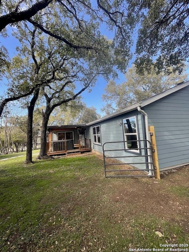 back of property featuring a deck and a lawn