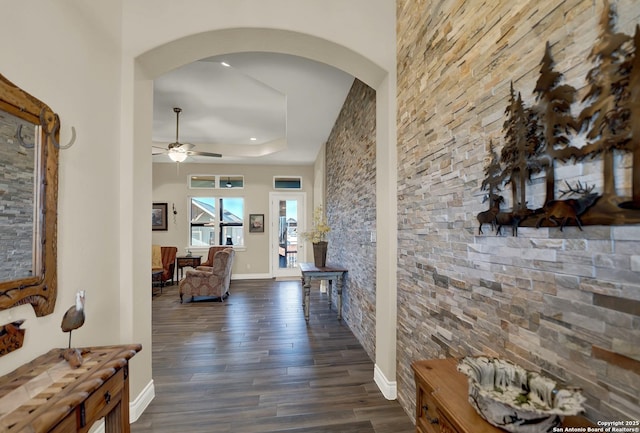 hall with dark wood-type flooring and a raised ceiling