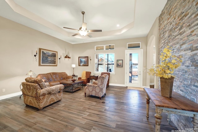 living room with dark hardwood / wood-style floors, ceiling fan, and a tray ceiling