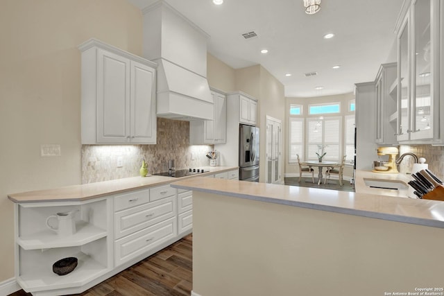 kitchen with stainless steel fridge with ice dispenser, kitchen peninsula, and white cabinets